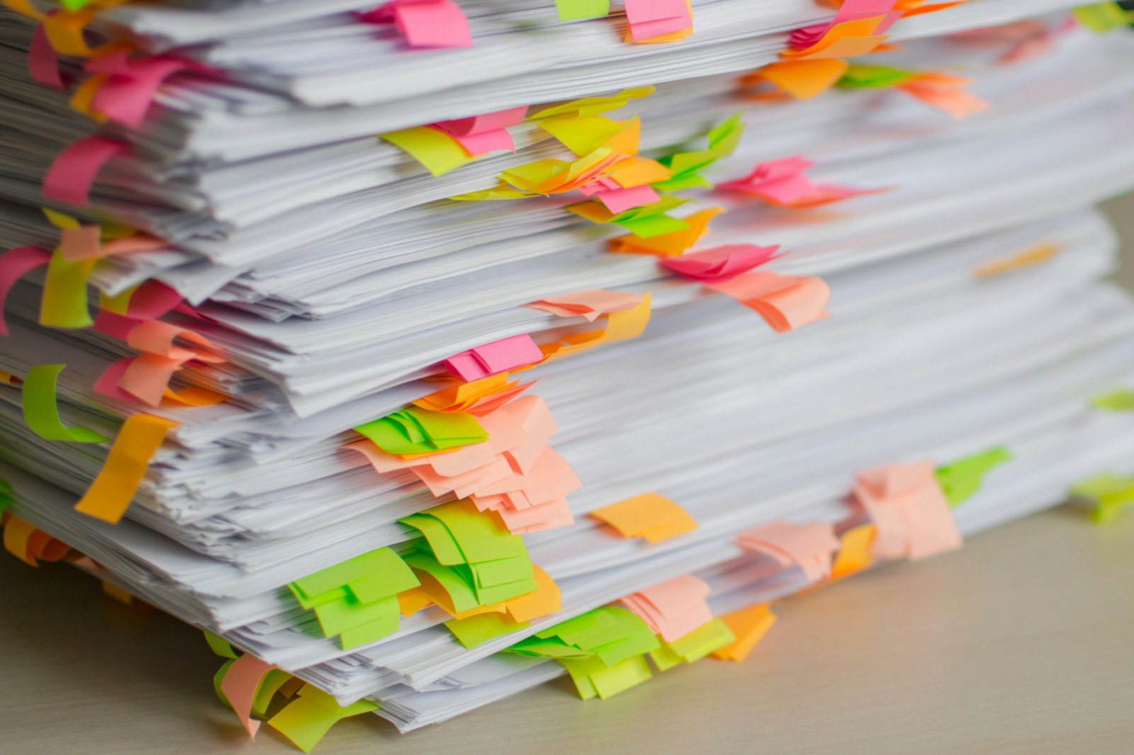 A tall stack of printed papers covered in pastel sticky tabs